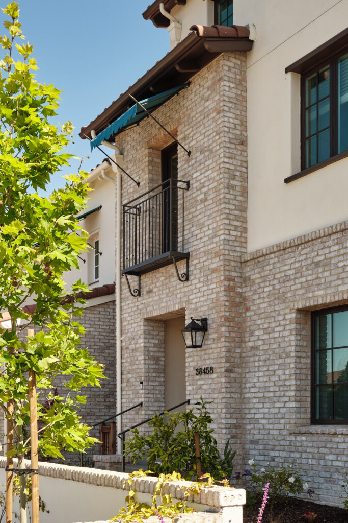 Corner exterior view with brick facade and balcony at Marabel in Newark, CA
