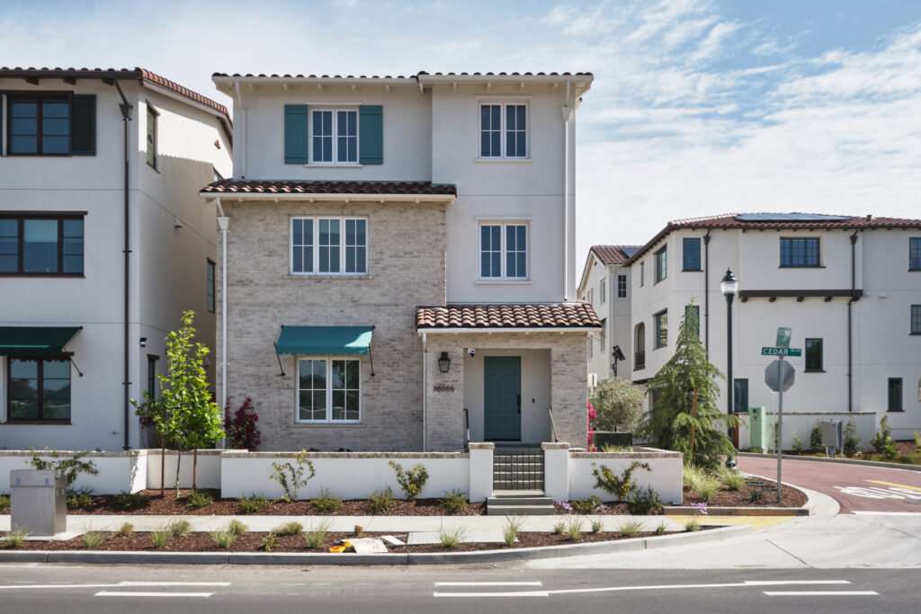 Corner street view of Marabel townhomes near a crosswalk in Newark, CA